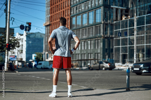Sportive man standing on street near crosswalk