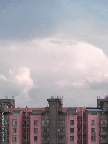 Pink-grey buildings under cloudy, white clouds