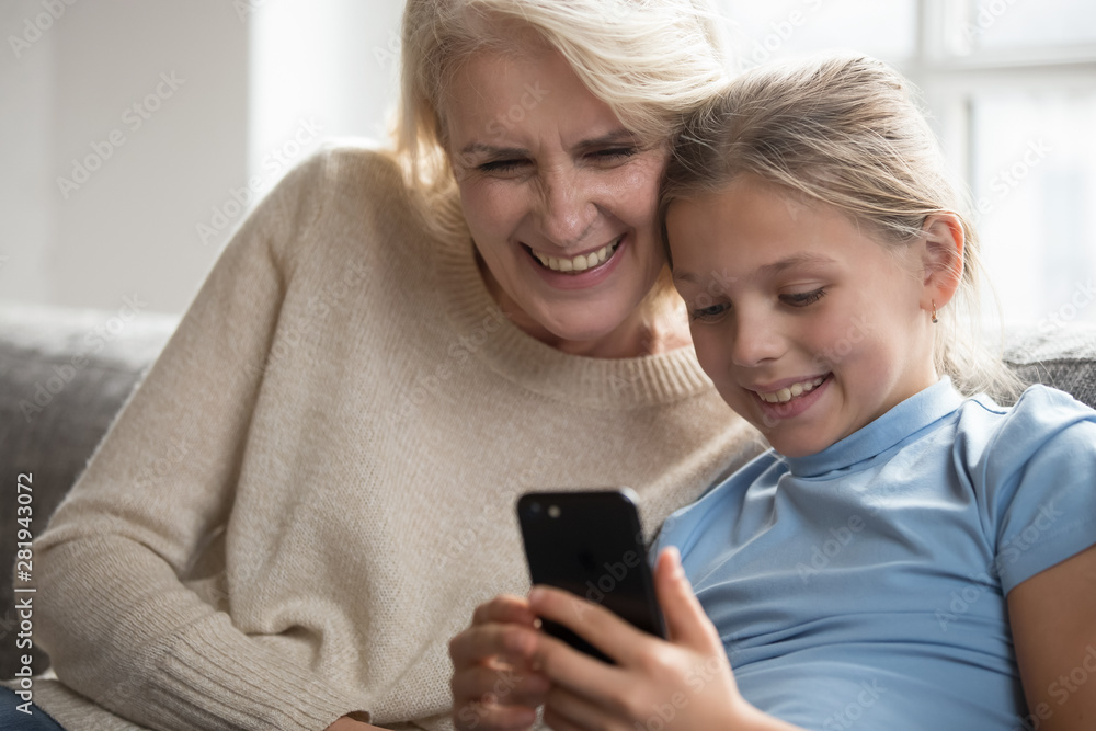 Grandmother and granddaughter having fun in internet using smartphone