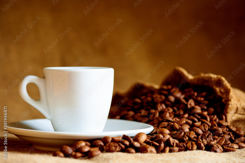 White cup and coffee beans on a blurred background. White cup and coffee beans on a blurred background.