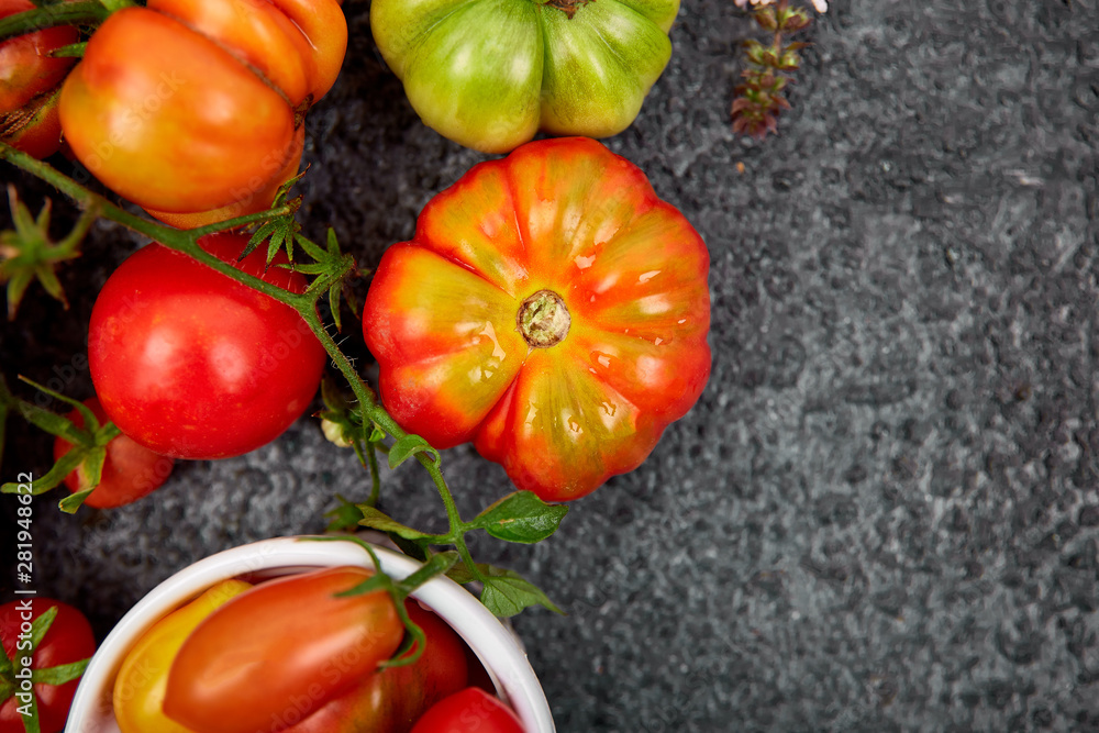 Mix of tomatoes background. Beautiful juicy organic red tomatoes on black table background. Clean eating concept. Copy space, flat lay.. Mix of tomatoes background. Beautiful juicy organic red tomatoes on black table background. Clean eating concept. Copy space, flat lay..