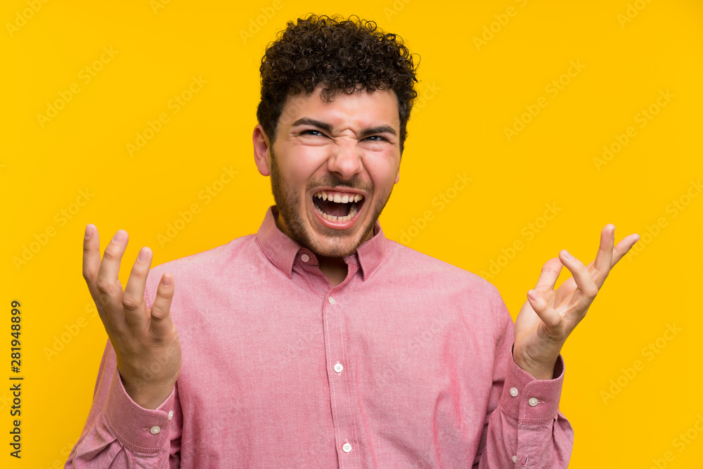 Man with curly hair over isolated yellow wall unhappy and frustrated with something Man with curly hair over isolated yellow wall unhappy and frustrated with something