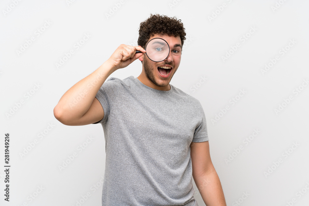Fototapeta premium Man with curly hair over isolated wall holding a magnifying glass