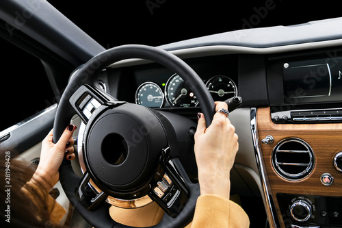 Woman's hands on the steering wheel driving modern luxury car. Concept woman driving. Hands holding steering wheel while driving. Car inside. Car detailing.
