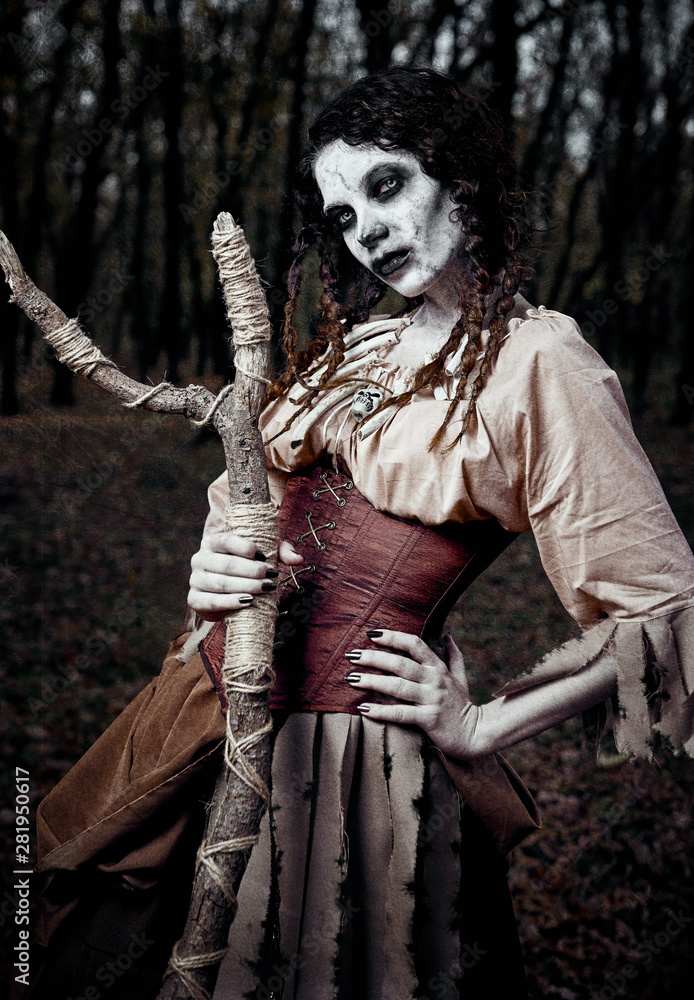 Halloween theme: gloomy creepy voodoo witch with stick. Portrait of evil hex in dark forest. Zombie woman (undead). Grunge texture effect Halloween theme: gloomy creepy voodoo witch with stick. Portrait of evil hex in dark forest. Zombie woman (undead). Grunge texture effect