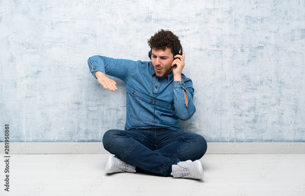 Young man sitting on the floor listening to music with headphones