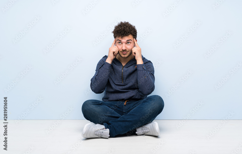 Young man sitting on the floor having doubts and thinking Young man sitting on the floor having doubts and thinking