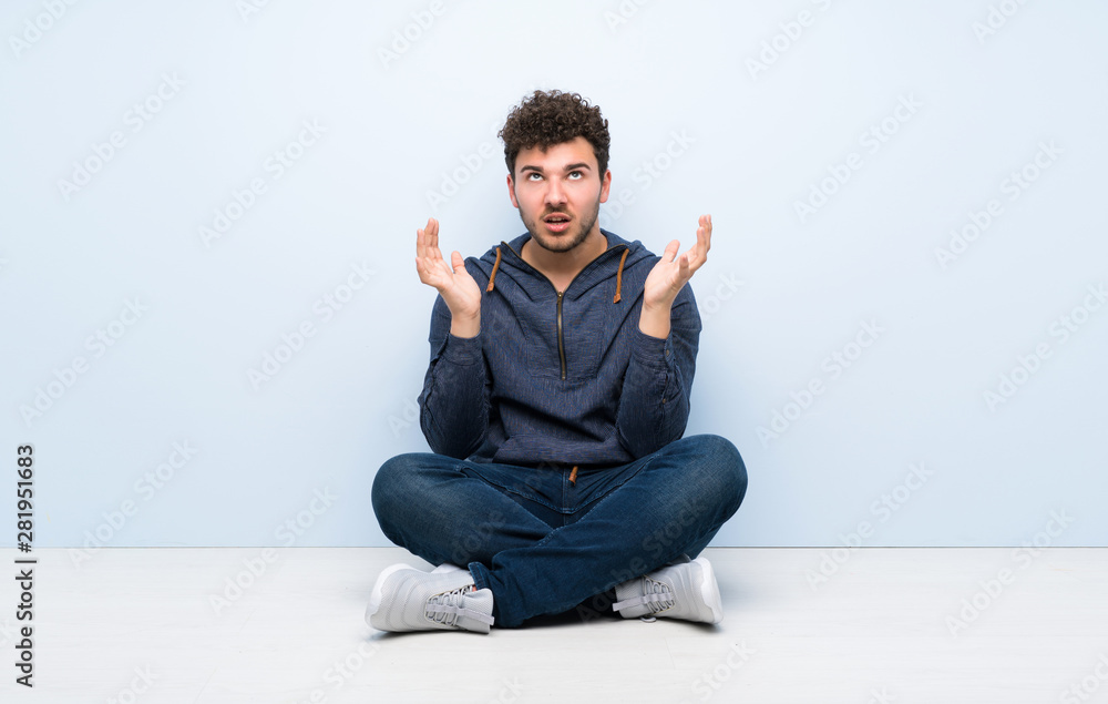 Young man sitting on the floor frustrated by a bad situation Young man sitting on the floor frustrated by a bad situation