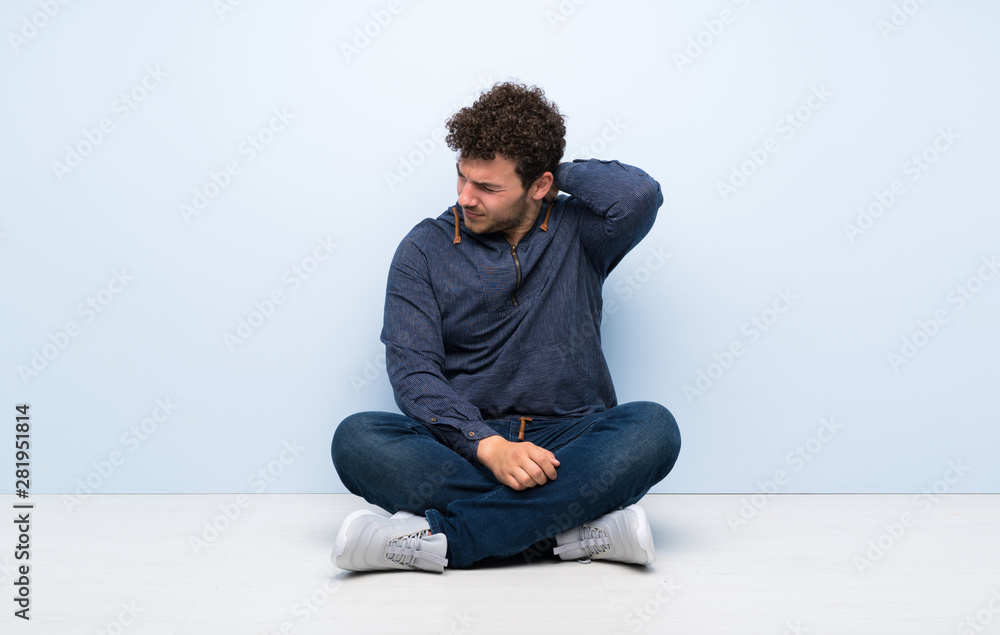 Young man sitting on the floor with neckache Young man sitting on the floor with neckache