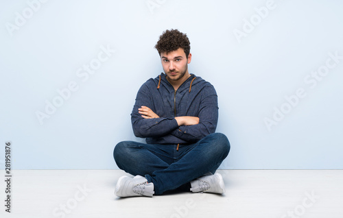 Young man sitting on the floor feeling upset