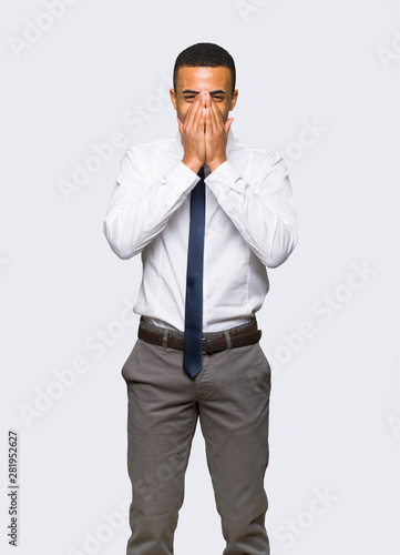 Young afro american businessman smiling a lot while covering mouth on isolated background