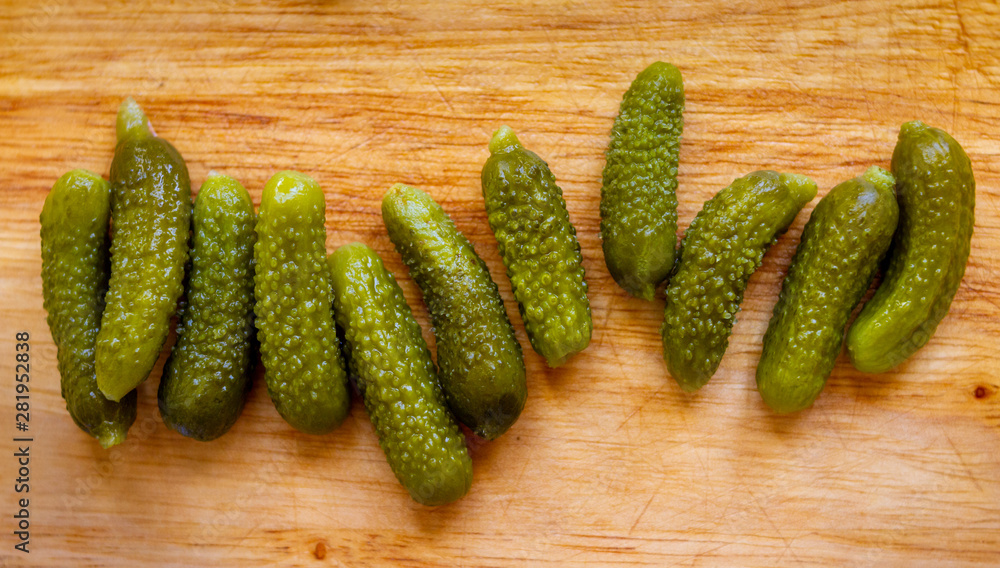 Full shot of some tiny pickled cucumbers in a wooden cutting board Full shot of some tiny pickled cucumbers in a wooden cutting board