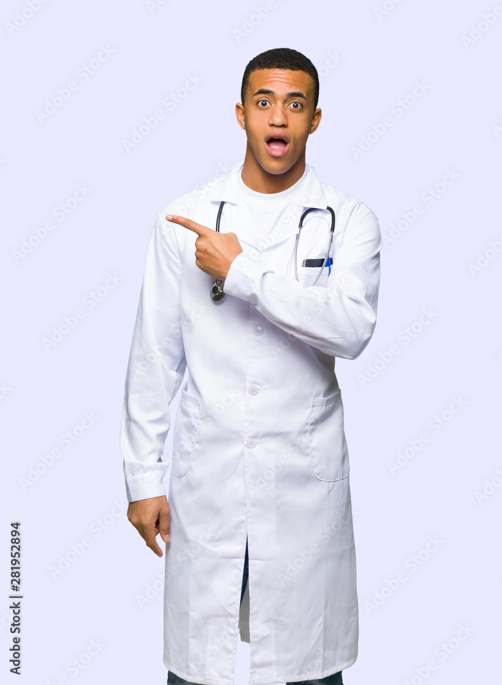 Young afro american man doctor surprised and pointing side on isolated background Young afro american man doctor surprised and pointing side on isolated background
