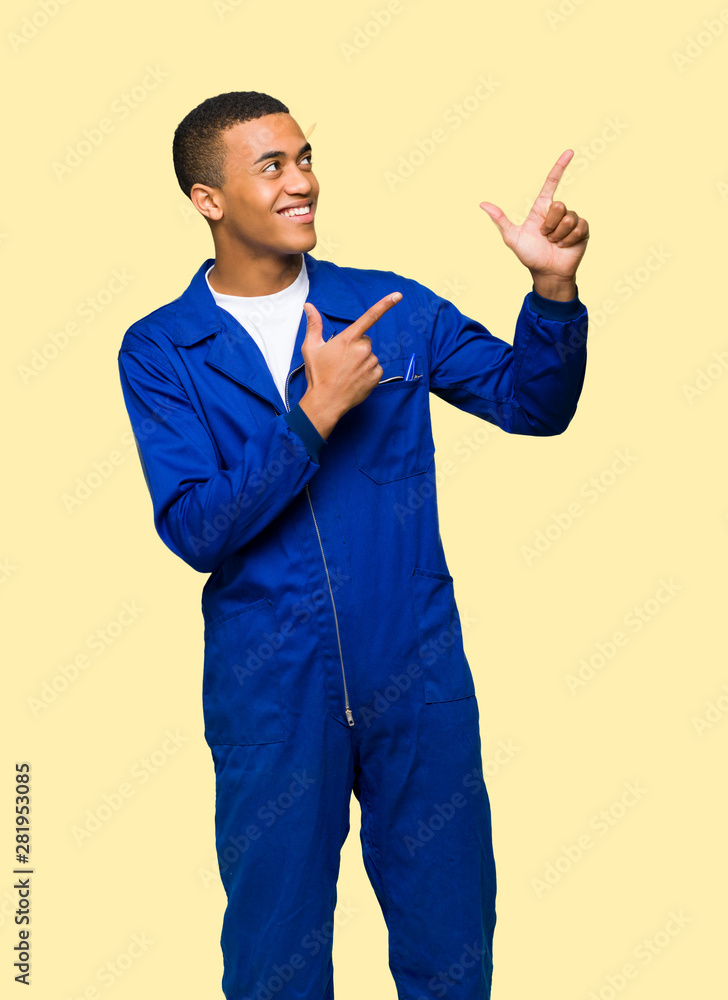 Young afro american worker man pointing with the index finger and looking up on isolated background Young afro american worker man pointing with the index finger and looking up on isolated background