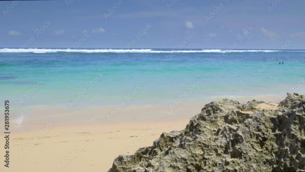 A handheld movement of beautiful vivid tropical beach with blue waves are hitting sand and swimming people A handheld movement of beautiful vivid tropical beach with blue waves are hitting sand and swimming people