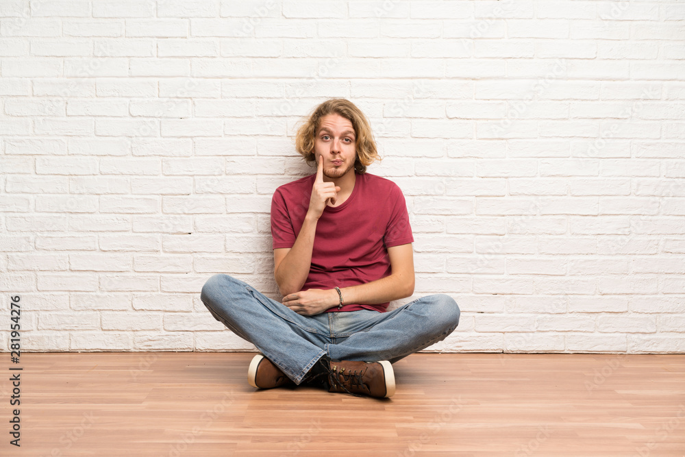 Blonde man sitting on the floor Looking front Blonde man sitting on the floor Looking front