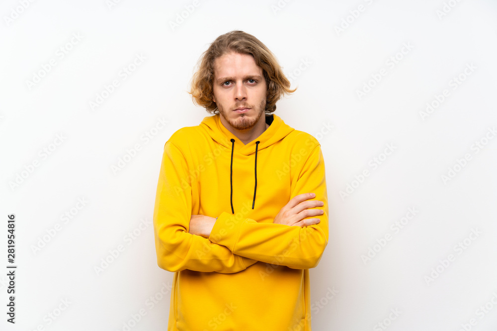 Blonde man with sweatshirt over white wall feeling upset Blonde man with sweatshirt over white wall feeling upset