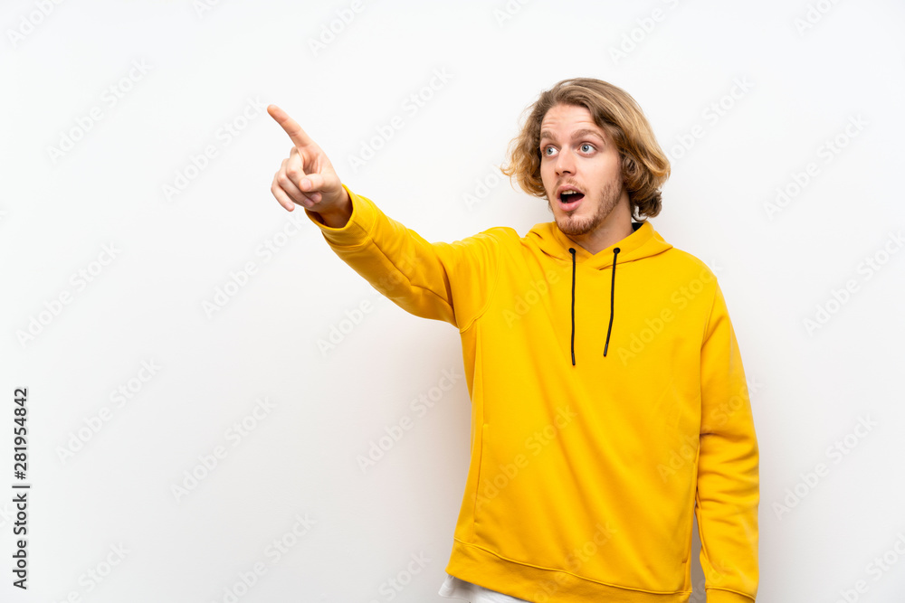Blonde man with sweatshirt over white wall pointing away Blonde man with sweatshirt over white wall pointing away