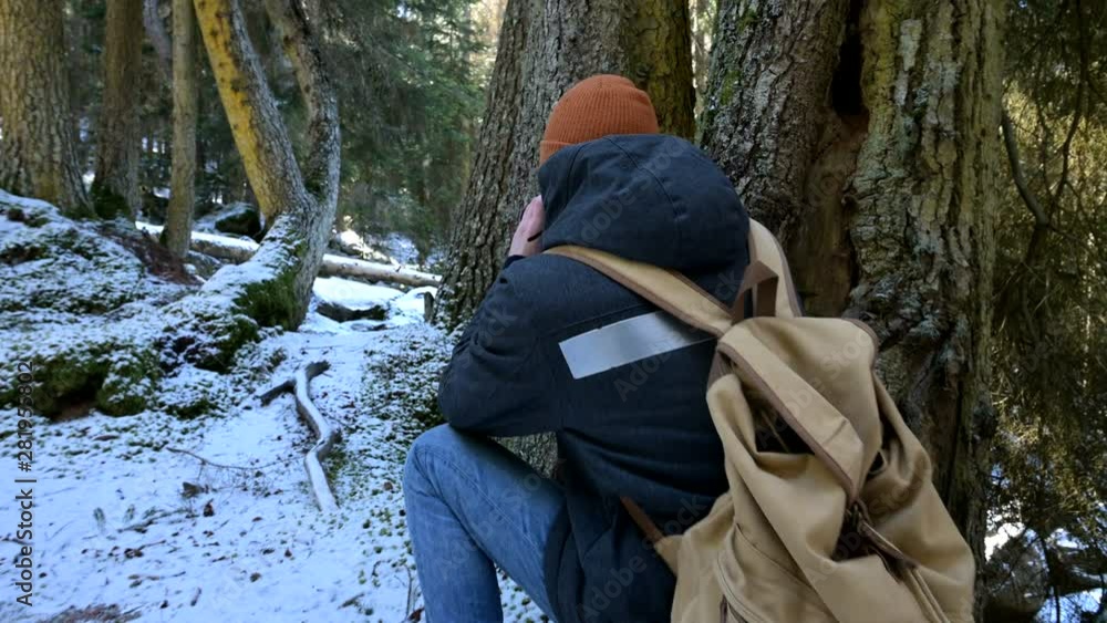 A bearded male traveler photographer with his camera in the winter forest takes pictures of nature. Travel concept for bloggers and photo artists A bearded male traveler photographer with his camera in the winter forest takes pictures of nature. Travel concept for bloggers and photo artists