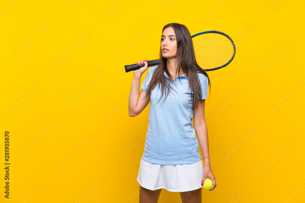 Young tennis player woman over isolated yellow wall Young tennis player woman over isolated yellow wall