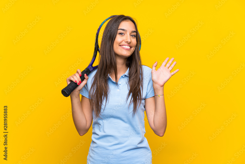 Young tennis player woman over isolated yellow wall saluting with hand with happy expression Young tennis player woman over isolated yellow wall saluting with hand with happy expression