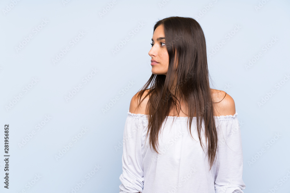 Young woman over isolated blue background looking side Young woman over isolated blue background looking side