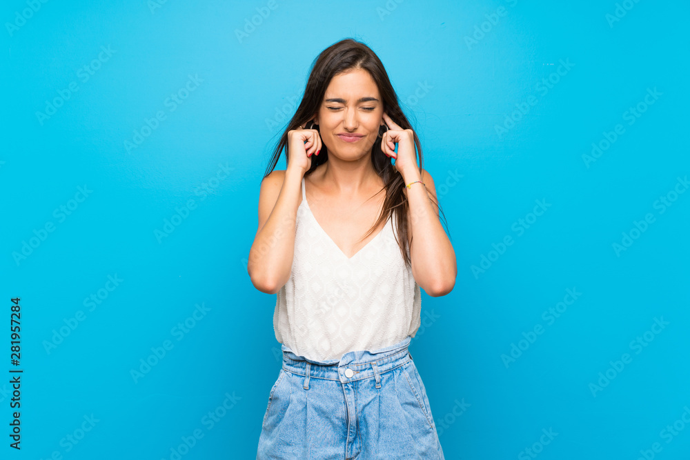Young woman over isolated blue background frustrated and covering ears Young woman over isolated blue background frustrated and covering ears