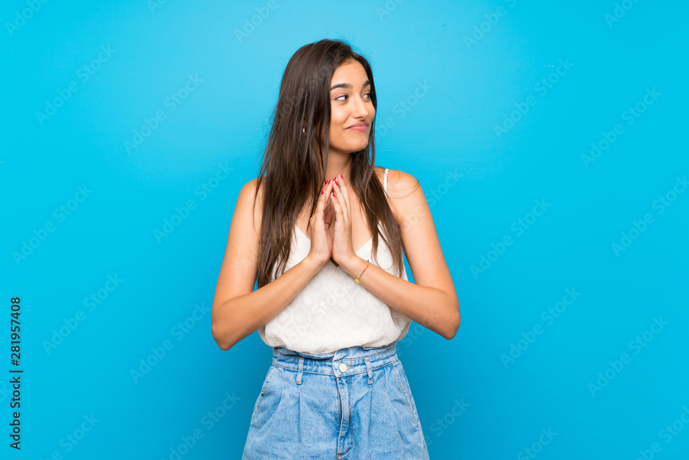 Young woman over isolated blue background points finger at you with a confident expression Young woman over isolated blue background points finger at you with a confident expression