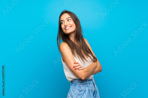 Young woman over isolated blue background Looking front