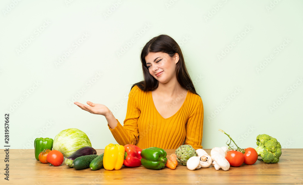 Fototapeta premium Teenager girl with many vegetables holding copyspace with doubts