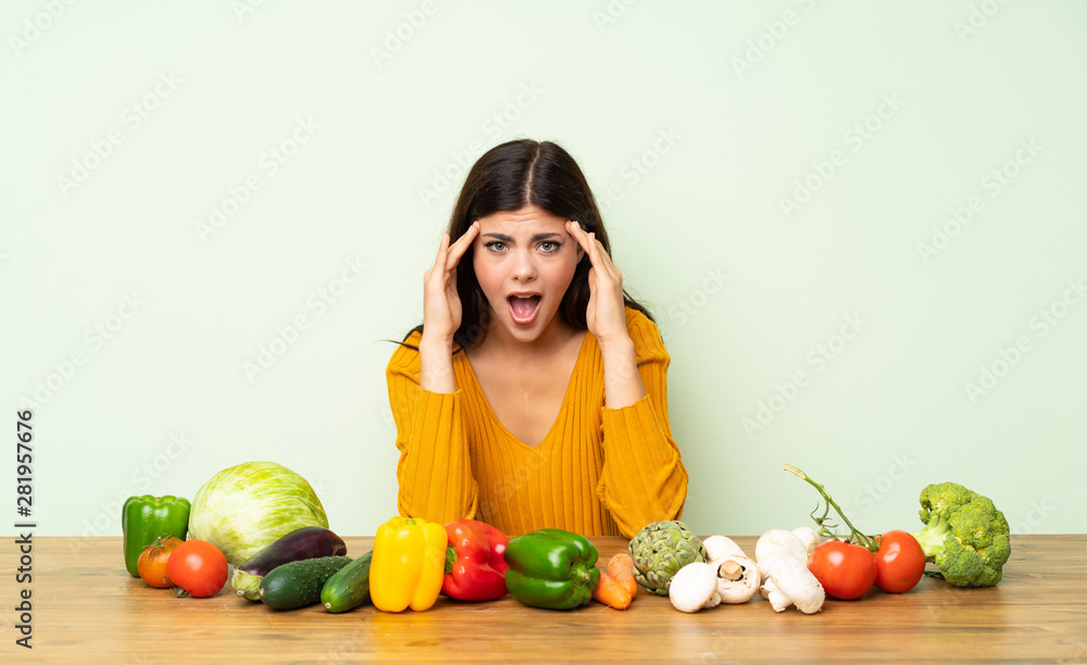 Fototapeta premium Teenager girl with many vegetables with surprise expression