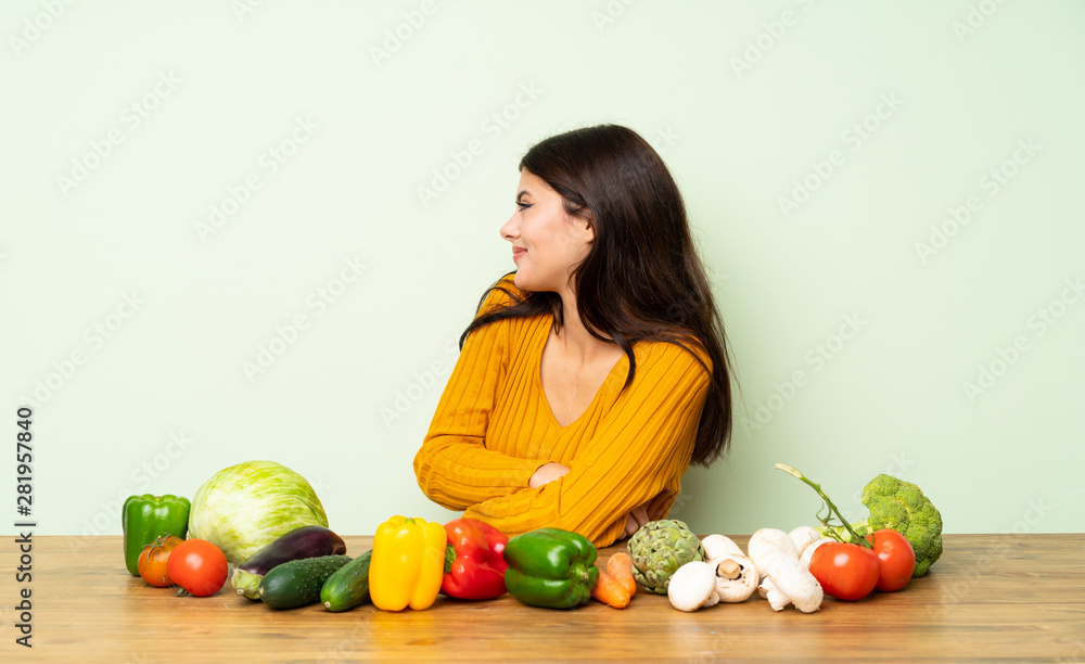 Fototapeta premium Teenager girl with many vegetables in lateral position