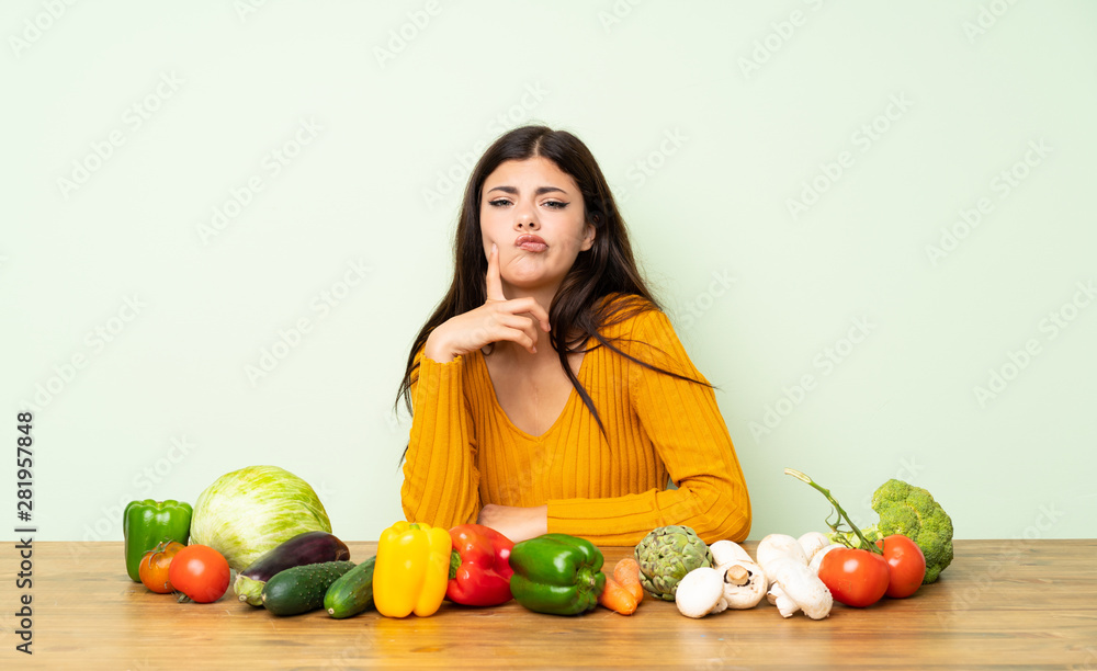 Fototapeta premium Teenager girl with many vegetables Looking front