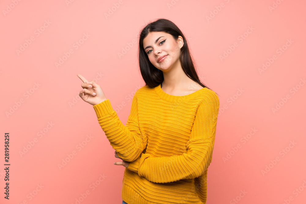 Teenager girl over isolated pink wall pointing finger to the side Teenager girl over isolated pink wall pointing finger to the side