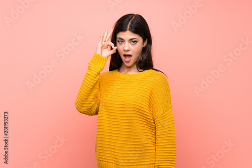 Teenager girl over isolated pink wall surprised and showing ok sign