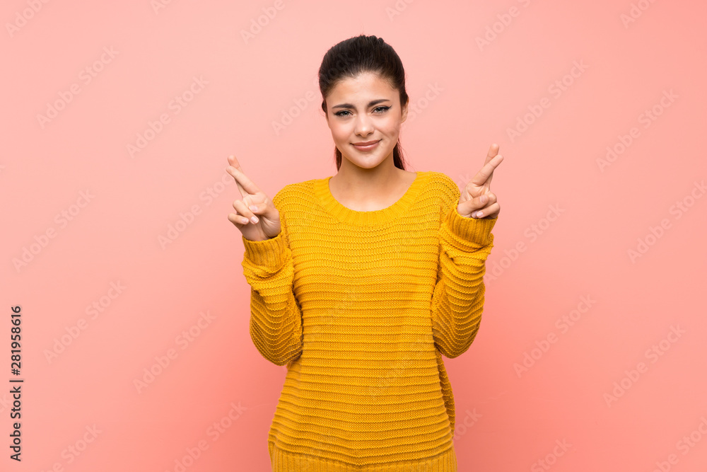 Teenager girl over isolated pink wall with fingers crossing and wishing the best Teenager girl over isolated pink wall with fingers crossing and wishing the best
