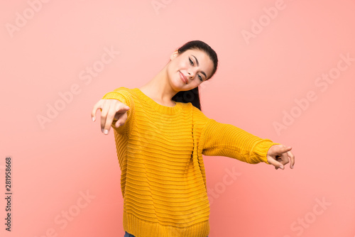 Teenager girl  over isolated pink wall points finger at you while smiling © luismolinero