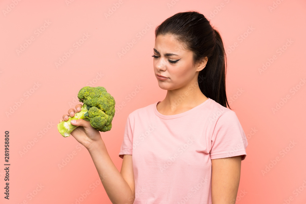 Teenager girl over isolated pink wall with a broccoli Teenager girl over isolated pink wall with a broccoli