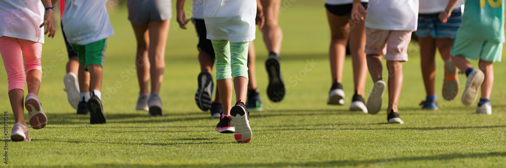 Running children, young athletes run in a kids run race, running on grass detail on legs, running in the light of morning Running children, young athletes run in a kids run race, running on grass detail on legs, running in the light of morning