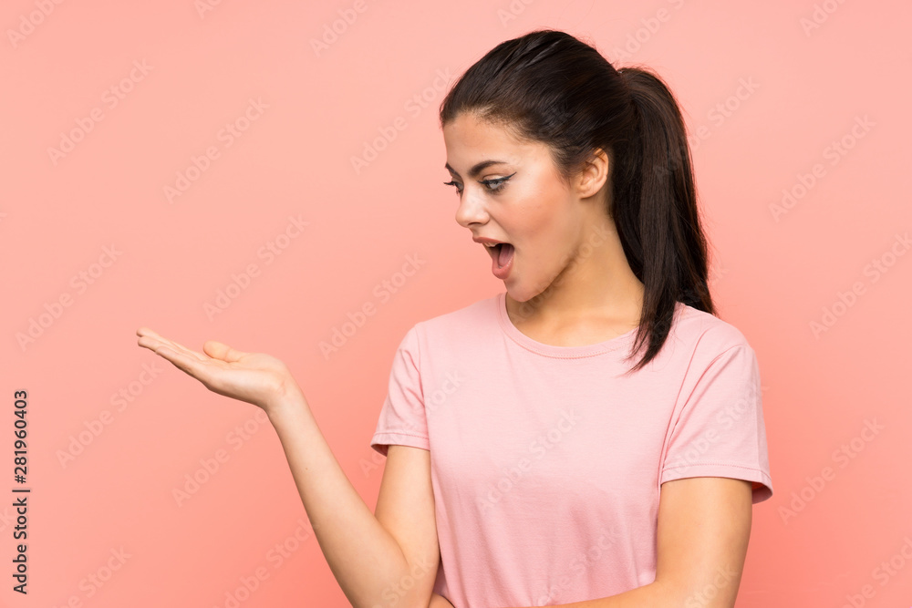 Teenager girl over isolated pink background holding copyspace imaginary on the palm Teenager girl over isolated pink background holding copyspace imaginary on the palm