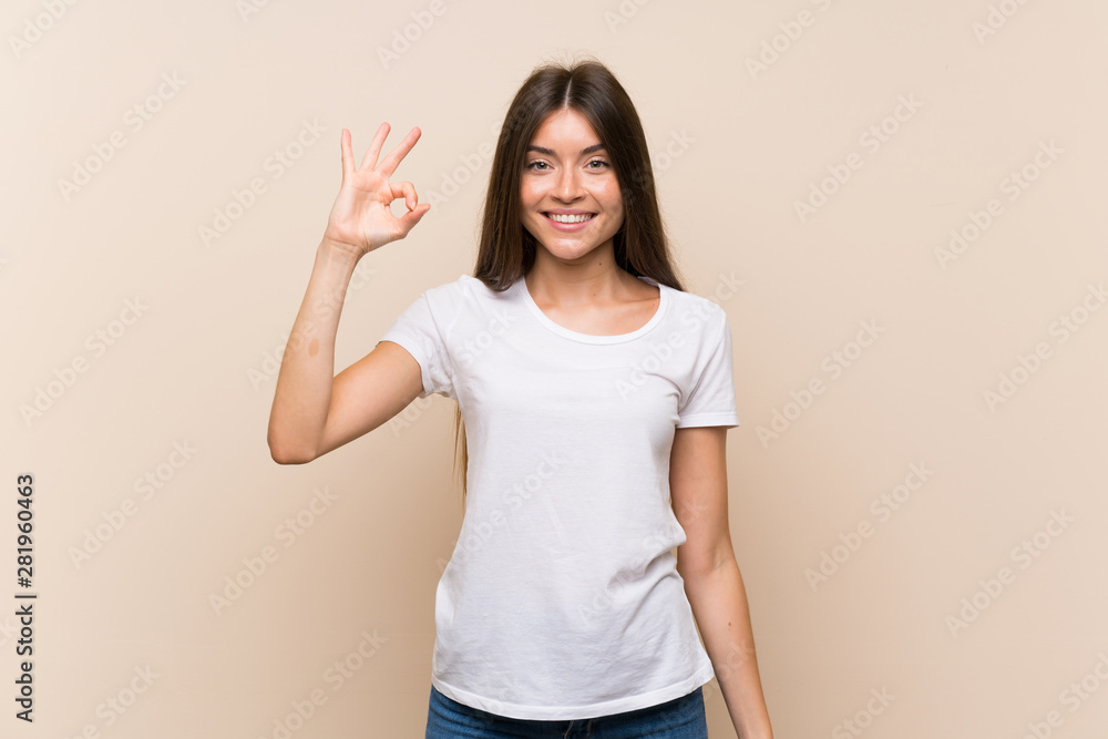 Pretty young girl over isolated background showing ok sign with fingers Pretty young girl over isolated background showing ok sign with fingers