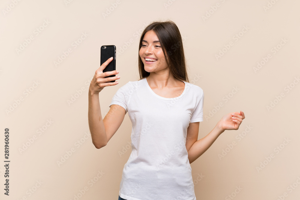 Pretty young girl over isolated background making a selfie Pretty young girl over isolated background making a selfie