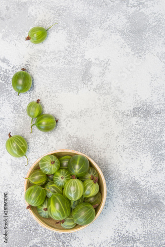 Green gooseberry in wooden plate on bright gray background. Recipe, diet, healthy food, cooking concept. Close-up, copy space, top view, flat lay, layout design