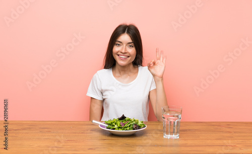 Young woman with a salad showing ok sign with fingers