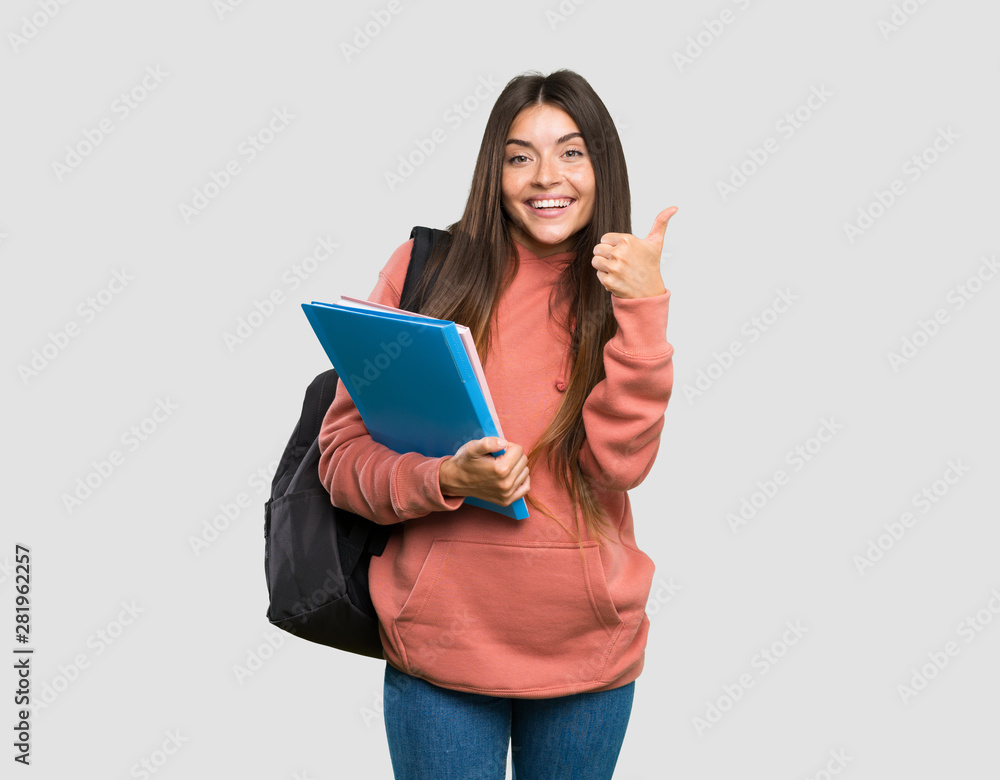 Young student woman holding notebooks showing ok sign and thumb up gesture over isolated grey background Young student woman holding notebooks showing ok sign and thumb up gesture over isolated grey background