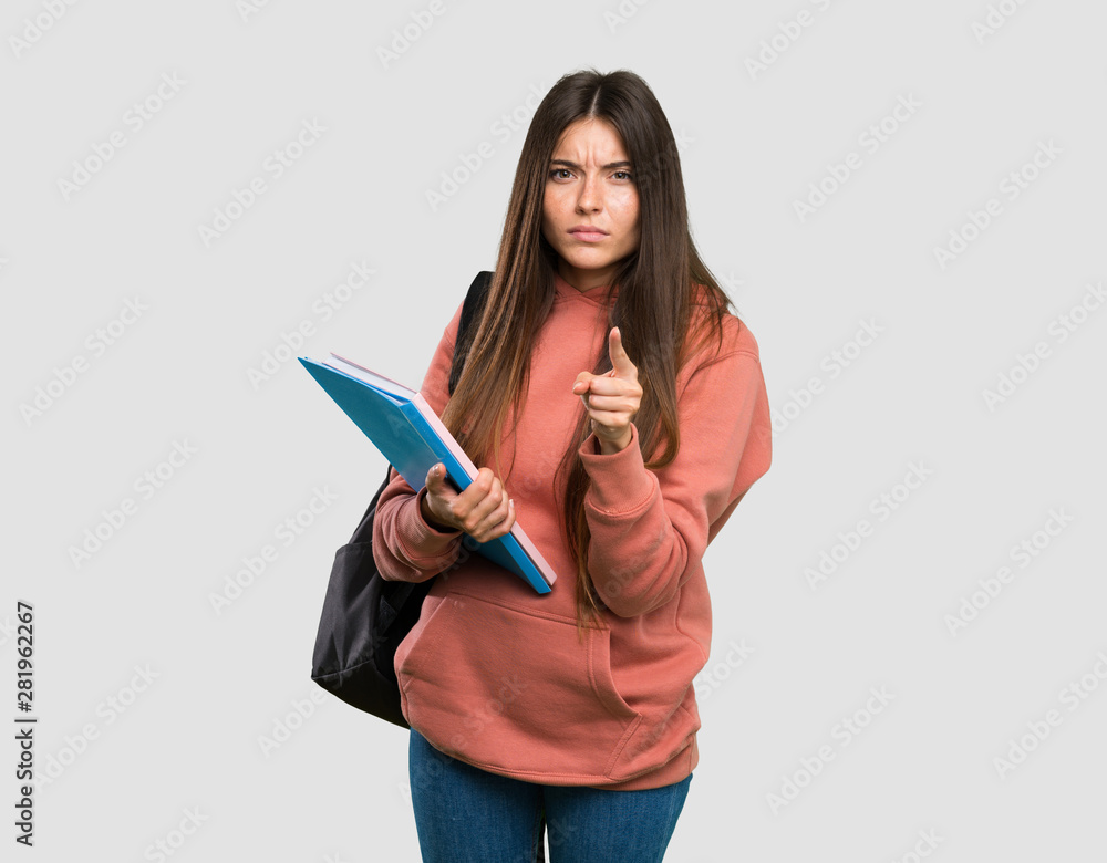 Young student woman holding notebooks frustrated and pointing to the front over isolated grey background Young student woman holding notebooks frustrated and pointing to the front over isolated grey background