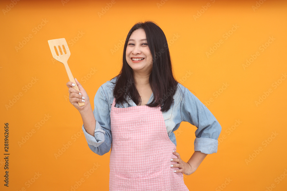 Happy Asian woman is cooking with apron for cooking advertise theme on on yellow background. Happy Asian woman is cooking with apron for cooking advertise theme on on yellow background.