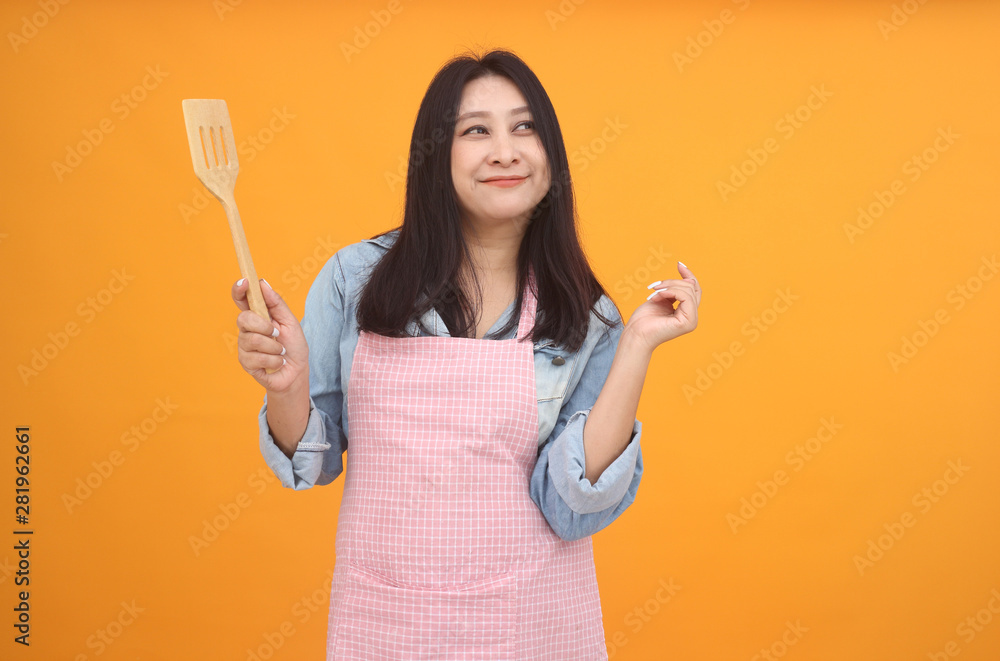 Happy Asian woman is cooking with apron for cooking advertise theme on on yellow background. Happy Asian woman is cooking with apron for cooking advertise theme on on yellow background.