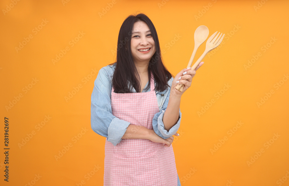 Happy Asian woman is cooking with apron for cooking advertise theme on on yellow background. Happy Asian woman is cooking with apron for cooking advertise theme on on yellow background.