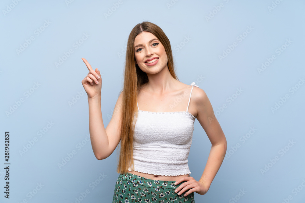 Young woman over isolated blue background showing and lifting a finger in sign of the best Young woman over isolated blue background showing and lifting a finger in sign of the best